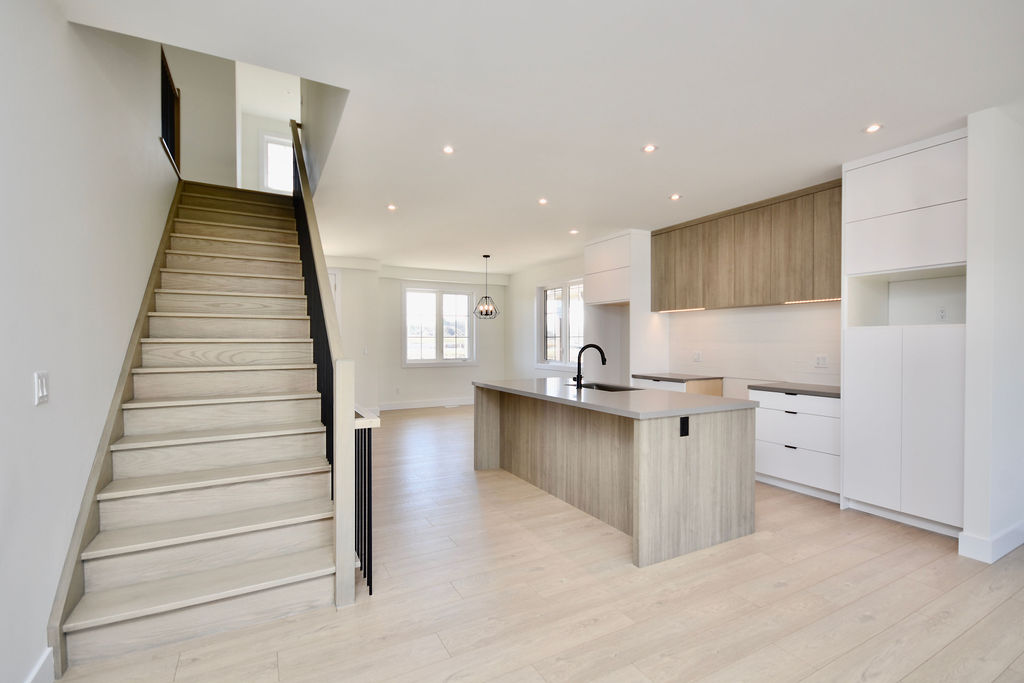 View of the kitchen toward the front of the home, and showing the staircase up to the second floor.